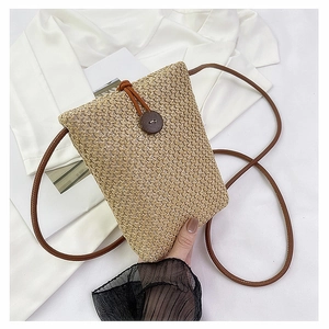 Close-up of beige woven straw phone bag with brown strap and decorative wooden button