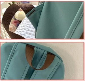 Close-up of reinforced stitching and brown nylon straps on a teal oxford fabric backpack