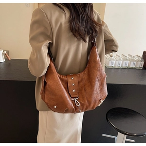 Détail d'un sac hobo en cuir marron avec rivets étoiles argentés et ferrures métalliques