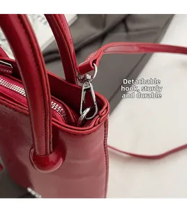 Macro detail of red high-gloss leather handbag with silver metal hook and zipper hardware