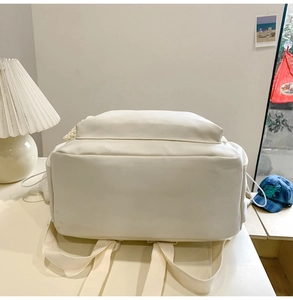 Detail of the reinforced shoulder straps and base on a minimalist white backpack