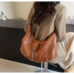 Détail d'un sac vintage marron avec clous étoilés et boucle à ressort sur la sangle