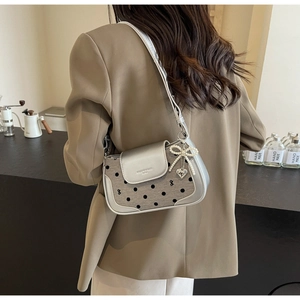 Polka dot shoulder bag with pearl bow and heart charm detail on a silver flap