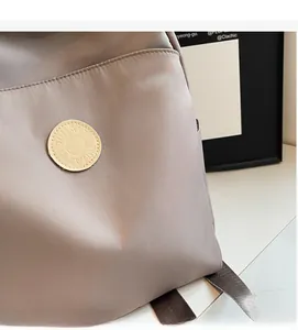 Close-up of soft nylon fabric texture and circular logo detail on the grey travel backpack