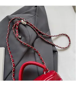 Detail view of red quilted bag with silver metal chain and heart-shaped lock on grey blazer