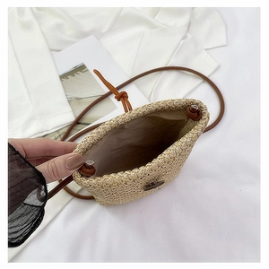 Close-up of beige woven straw crossbody bag interior with brown cord strap and fabric lining