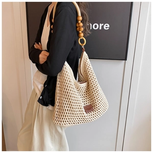 Détail du sac cabas beige tissé main montrant les bretelles en bois et le patch logo
