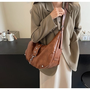 Détail du sac hobo marron avec des rivets en forme d'étoile argentée sur la bandoulière