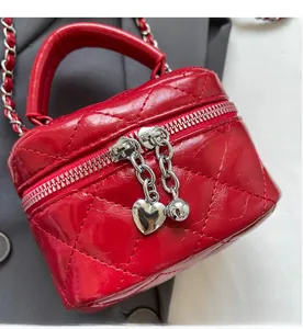 Detailed macro view of red quilted leather mini box bag with heart charms and silver chain