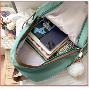 Detail view of mint green canvas backpack showing spacious storage with laptop and books