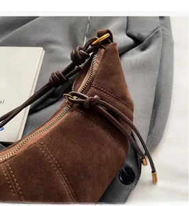 Detail of brown suede croissant bag featuring smooth zipper and premium texture