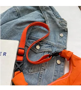 Détail de la bandoulière réglable orange avec boucle noire sur un sac à bandoulière