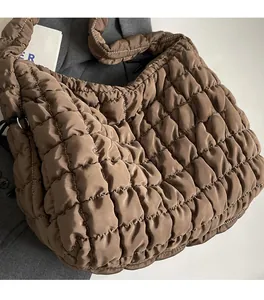 Detail of dark brown quilted puffer bag with white contrast stitching on the strap