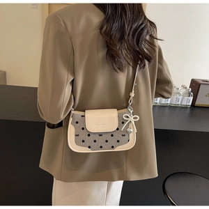Detail of canvas crossbody bag with polka dot print, bow embroidery, and pearl charm