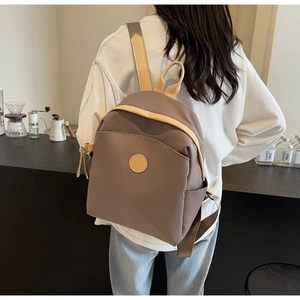 Detail view of khaki commuter backpack on model in a cozy, minimalist cafe setting