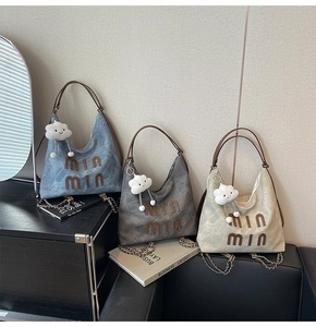 Close-up of stylish faux leather tote bags in blue, grey, and cream with plush cloud charms