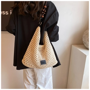 Détail du sac à bandoulière en maille avec perles en bois et écusson logo de la marque