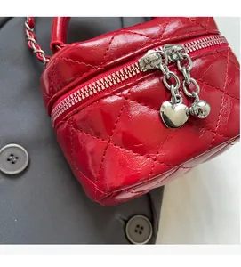 Detail of red quilted mini box bag with silver heart charms and chain strap