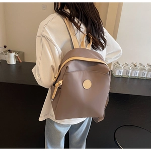 Detail view of stylish taupe nylon backpack with beige accents worn by a model