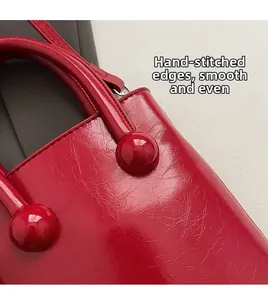 Detail of red leather bag with hand-stitched edges and smooth polished finish