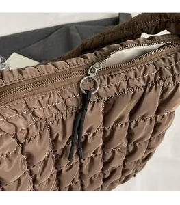 Close-up of smooth metal zipper and brown quilted nylon fabric on the puffy cloud bag