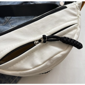 Dettaglio della cerniera nera e della tela di nylon resistente del marsupio bianco
