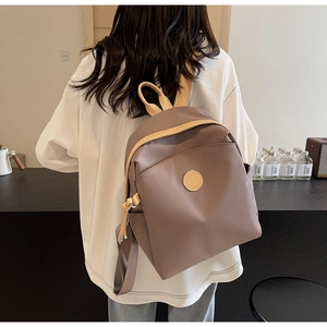 Detail showing mocha brown nylon fabric and leather logo patch on stylish backpack