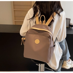 Close-up side view of a stylish grey-brown nylon travel backpack with beige straps