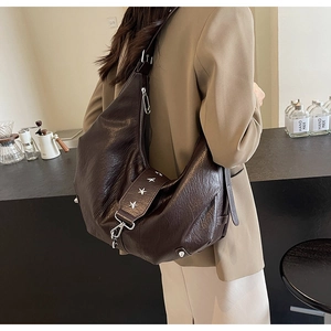 Détail du sac croissant marron foncé avec rivets étoiles et texture en cuir vintage