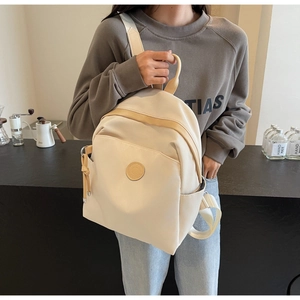 Beige travel backpack with brown leather details displayed on a coffee shop bar background