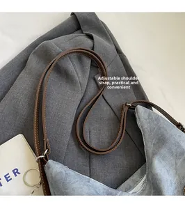 Detail view of denim tote bag with adjustable brown leather strap and contrast stitching
