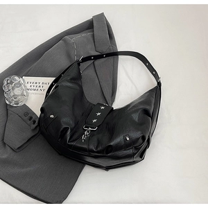 Détail du sac croissant noir avec clous étoiles argentés et texture plissée rétro