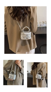 Detail of silver quilted mini box bag with chain strap and heart charm zipper