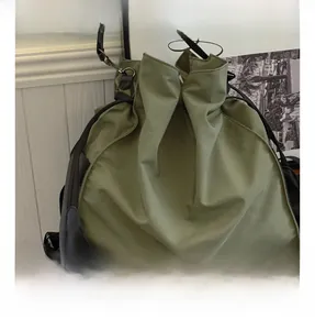 Close-up of sage green nylon tote bag showing material texture and drawstring detail