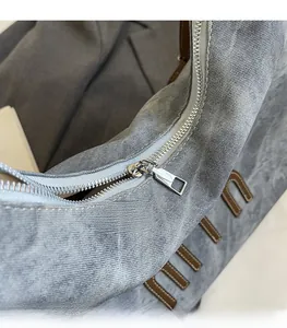 Detailed macro view of the silver metal zipper and denim fabric on the tote bag