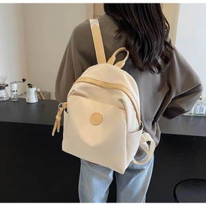 Detailed back view of a beige nylon mini backpack with logo on a lifestyle background