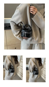 Detail of a black quilted mini bucket bag with silver chain strap and top handle