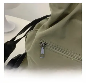 Close-up of smooth silver zipper and black strap on olive green nylon tote bag