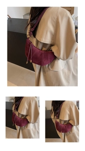 Detail of burgundy frosted leather croissant bag with pleated seams and gold hardware