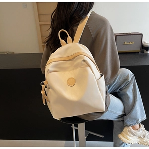 Close-up of beige waterproof nylon backpack with front pocket and side storage detail