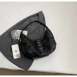 Détail du sac hobo noir avec des clous en étoile argentés et boucles métalliques