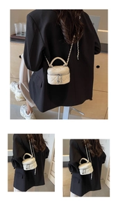 Detail of white quilted vanity bag featuring silver chain strap and heart charm
