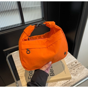 Détail du sac demi-lune en nylon orange montrant la poche zippée et la boucle de fermeture