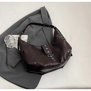 Vue détaillée du cuir marron foncé et du rivet en étoile argenté sur le sac à bandoulière