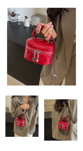 Detail of red quilted mini box bag with metallic heart charms and chain strap