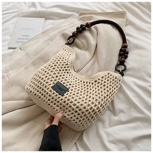 Détail du sac beige tissé main avec perles en bois sur la bandoulière et étiquette en cuir