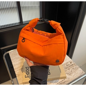 Détail du sac à main en nylon orange montrant la texture mesh et la boucle en plastique