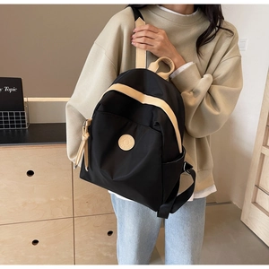Detail of a black and white contrast backpack shown on a model in a casual setting