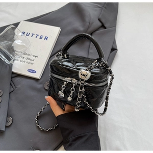 Detail of black quilted mini vanity bag with silver chain and heart pendant