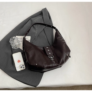Détail d'un sac hobo marron foncé avec rivets étoiles argentées et fermoir mousqueton
